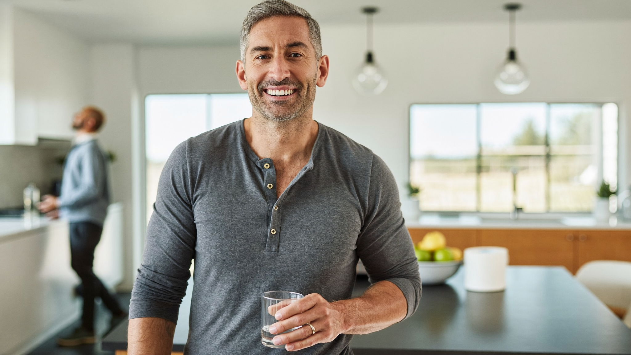 A healthy man in his late 40s in a bright kitchen, choosing an at-home testosterone test kit